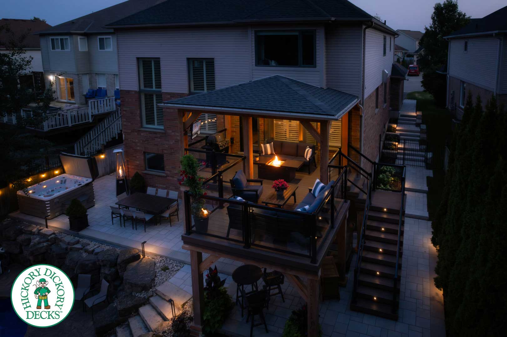 Two-story deck and patio illuminated at night.