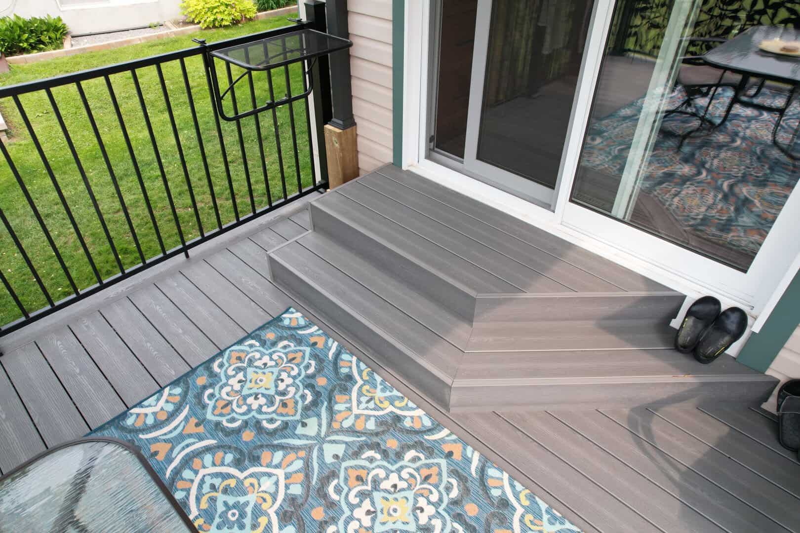 Deck with a rug and two stairs along with railings